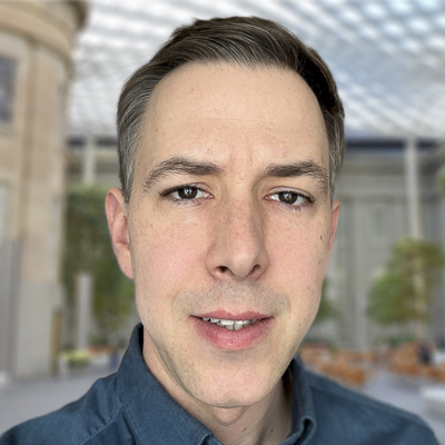 a person with dark hair and a blue collared shirt in a museum